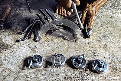 Hands of a senior mechanic repair and replace new wheels on sliding track of stretched steel door. Installation of new steel Stock Photo