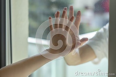 Hands separated by a glass window for social distancing during the corona virus lockdown Stock Photo