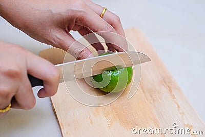Hands slicing a lime with a chef knife Stock Photo