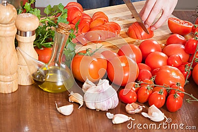 Hands slicing tomatoes at table Stock Photo