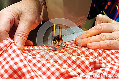 Hands stitching denim cloth with a sewing machine Stock Photo