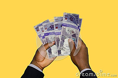 Black Hands in suit holding 3D rendered Qatar Riyal notes Stock Photo