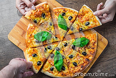 Hands take a slice of Pizza with Mozzarella cheese, Tomatoes, pepper, olive, Spices and Fresh Basil. Italian pizza. Pizza Margheri Stock Photo