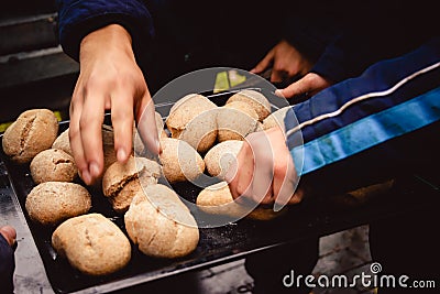Hands taking out home made small wheat corn breads out of stove Stock Photo