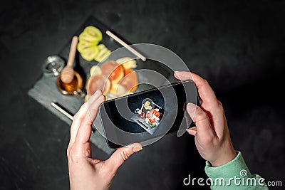 Hands taking photo a cottage cheese pancakes and honey with smartphone Stock Photo