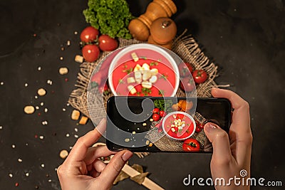 Hands taking photo a delicious tomato soup in a ceramic bowl with smartphone Stock Photo