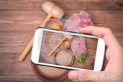 Hands taking photo raw pork schnitzel with smartphone. Stock Photo