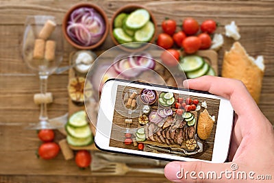 Hands taking photo sliced grilled meat barbecue with smartphone. Stock Photo