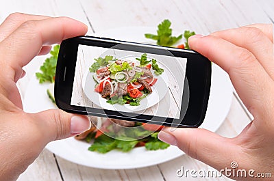 Hands taking photo vegetable salad with meat with smartphone Stock Photo