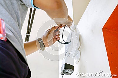 Hands of technician is working connecting power cords to install the CCTV on building wall Stock Photo