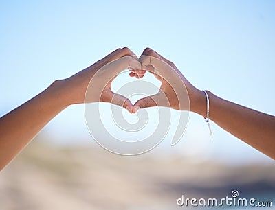 Hands together, heart sign and outdoor at beach, nature and blue sky in blurred background for love. Couple, hand touch Stock Photo