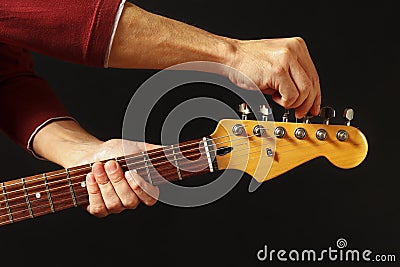 Hands tunes the guitar on black background Stock Photo