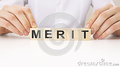 the hands turns the wooden cube and word Merit Stock Photo