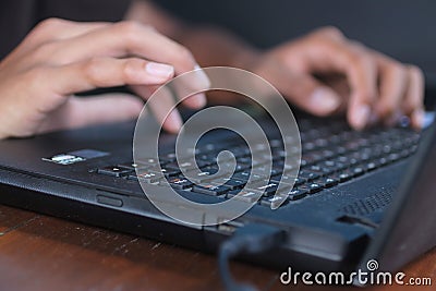 Hands typing on black laptop keyboard. Young man doing business or homework by searching, browsing information from internet. Stock Photo