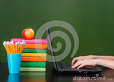 Hands typing on notebook near empty green chalkboard Stock Photo