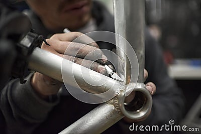 Hands of an unrecognizable hispanic man removing paint residue from a bike frame Stock Photo
