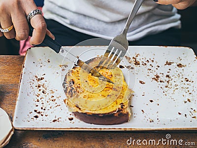 Hands using knife and fork to cut cheese toast Stock Photo