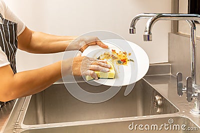 Hands washing dirty dishes in kitchen sink Stock Photo
