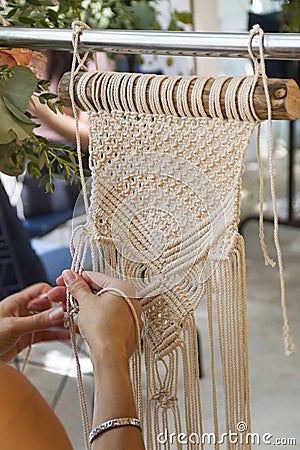 Hands weaving macrame tapestry with beige thread Stock Photo