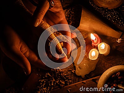 In the hands of witches chicken leg for divination. The light from the candles on the old magic table. Attributes of occultism and Stock Photo