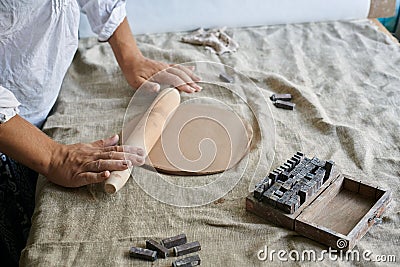 hands of a woman artisan ceramist kneading a layer of clay on the table close-up Stock Photo