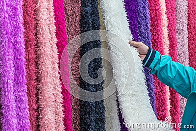 Hands of woman checking and choosing variety of beautiful colorful cloth made from bamboo pulp for good health hanging for sale in Stock Photo