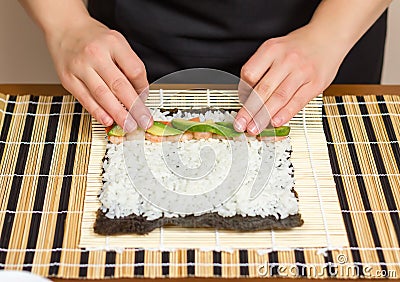Hands of woman chef rolling up a japanese sushi Stock Photo