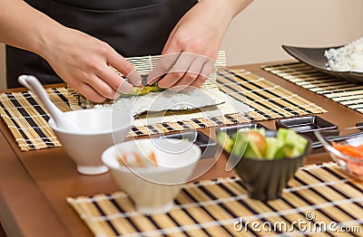 Hands of woman chef rolling up a japanese sushi Stock Photo