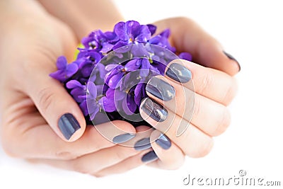 Hands of a woman with dark manicure on nails and bouquet of violets on a white background Stock Photo