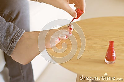 Hands of a woman painting her foot nails with red nail polish. Personal care. Photo with no visible faces. Concept of personal Stock Photo