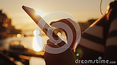 Hands of a woman with a smartphone on the background of a pier with yachts at sunset Stock Photo