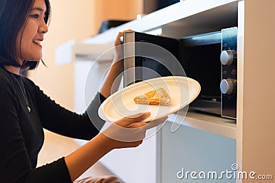 Hands woman using microwave oven with bread in home kitchen Stock Photo