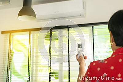 Hand using a remote control to activating air conditioning at reception room Stock Photo