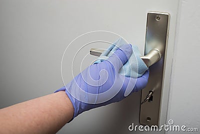 hands of woman wearing latex gloves cleaning the handle of the door to protect against the coronavirus pandemic Stock Photo