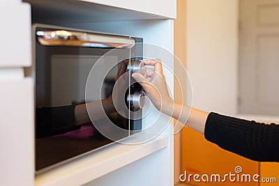 Hands woman using microwave oven in home kitchen Stock Photo