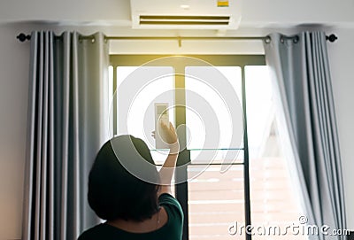 Hands woman using on off a remote control to activating air conditioning system in bedroom Stock Photo