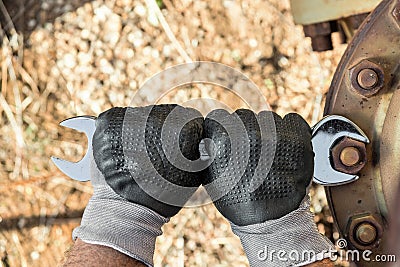 Hands with Work Gloves Holding a Wrench and Tighten very Rusty Bolts Stock Photo