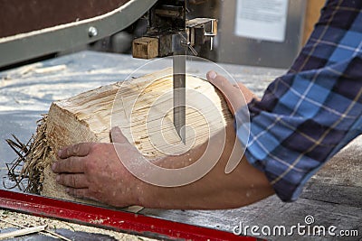 Hands of a worker sawing firewood with an industrial bandsaw Stock Photo