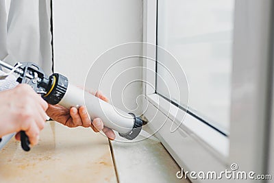 Hands of worker using a silicone tube for repairing of window Stock Photo