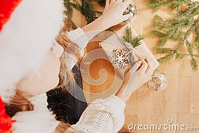 Hands wrapping present boubles christmas tree branches with face Stock Photo