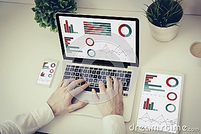 hands writing on a laptop with tablet and phone finances graphic Stock Photo
