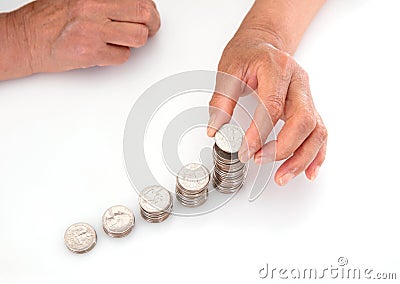 Hands with yellow skin looking down on white background are stacking dollar coins Stock Photo