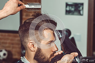 The hands of young barber making haircut to attractive man in barbershop Stock Photo