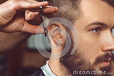 The hands of young barber making haircut to attractive man in barbershop Stock Photo