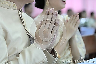 Hands of young couple praying in Thai wedding ceremony. Selective focus and shallow depth of field. Stock Photo