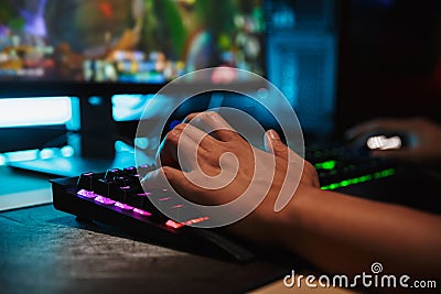 Hands of young gamer man playing video games on computer in dark Stock Photo