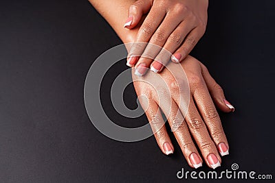 The hands of a young girl are covered with a highlight top. French manicure. Hands on a black background Stock Photo
