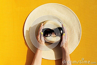 Hands of young girl holding straw hat and sunglasses on vibrant Stock Photo