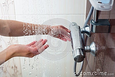 Hands of a young woman taking a hot shower Stock Photo