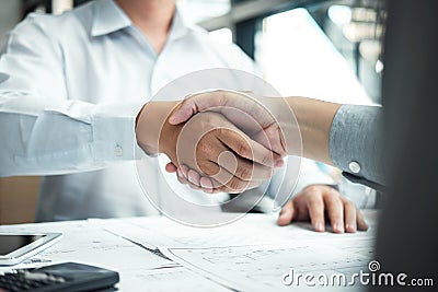 Handshake of collaboration, Construction engineering or architect discuss a blueprint and building model while checking Stock Photo